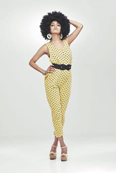 Shes a disco diva. Full length shot of young woman wearing a 70s retro jumpsuit striking a pose in studio.