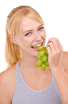 Grapes are great. Portrait of a young woman eating grapes isolated on white.