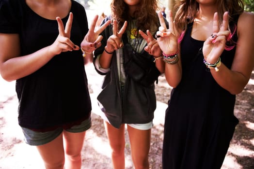 Peace and love. Three friends showing the peace sign while at an outdoors festival