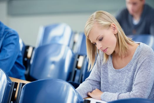 Considering her answer carefully. an attractive college student studying in a lecture hall.
