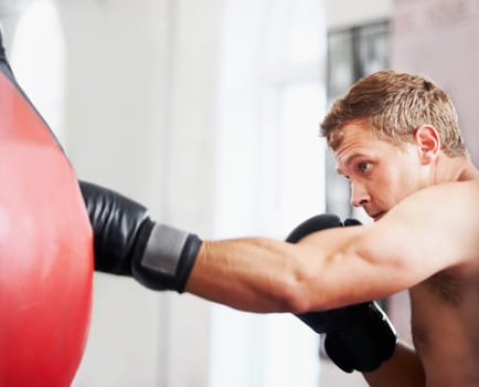Strength and focus. A young boxer practicing with a punching ball.