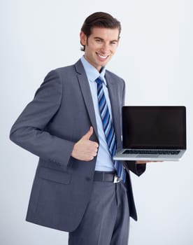 Invaluable business tool. A young businessman endorsing a laptop with a thumbs up.