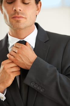 You have to look the part. Cropped image of a young businessman adjusting his tie before going to work.