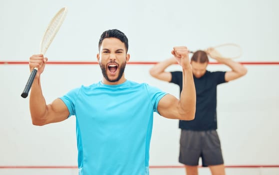 Young athletic squash player winning after playing opponent in competitive court game. Fit active mixed race athlete celebrating success after training challenge in sports centre. Excited sporty man