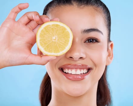 No half measures in the pursuit of beauty. Studio portrait of an attractive young woman posing with half a lemon against a blue background.