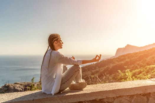 Yoga woman mountains. Profile of a woman doing yoga in the top of a cliff in the mountain. Woman meditates in yoga asana Padmasana