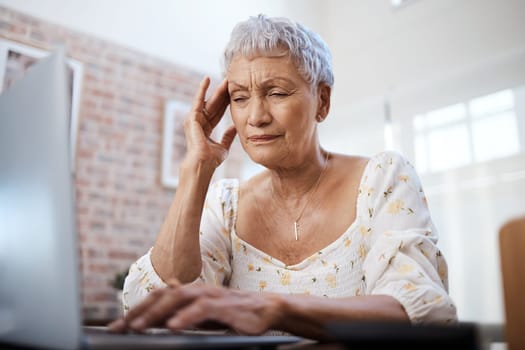 This was not part of the retirement package. a senior woman looking stressed while using a laptop at home.