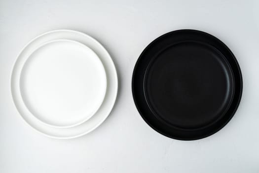Empty ceramic plate, black and white on a concrete white background. Stylish tableware