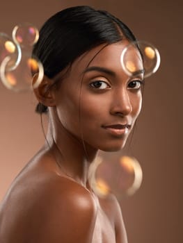 Ill never leave these living walls. Portrait of a young attractive woman posing with bubbles against a brown background.