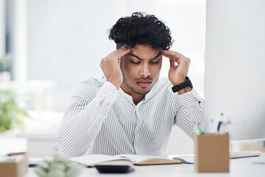 I just cant make any sense of this. a young businessman looking stressed out while working in an office.