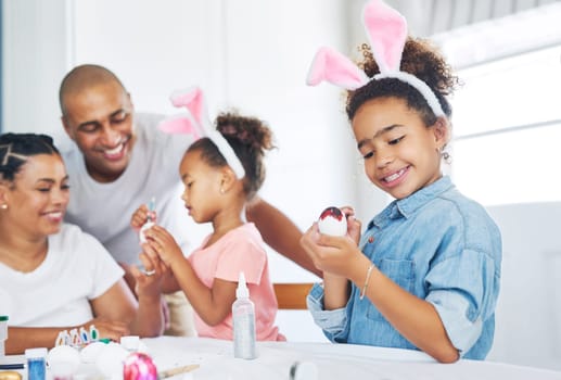 Creativity is contagious, pass it on. a mother and father painting eggs with their daughter at home