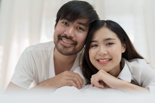 Asian Romantic couple in bed enjoying sensual foreplay Happy sensual young couple lying in bed together. Beautiful loving couple kissing in bed.