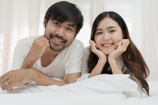 Asian Romantic couple in bed enjoying sensual foreplay Happy sensual young couple lying in bed together. Beautiful loving couple kissing in bed.