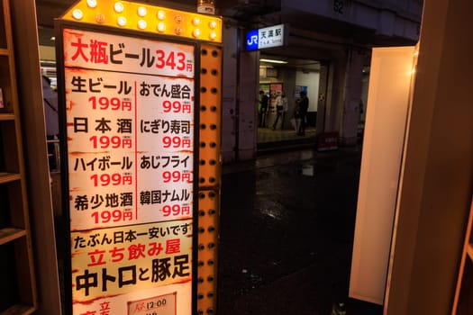 Osaka, Japan - April 29, 2023: Illuminated sign in Japanese with prices for bar food at restaurant by station . High quality photo