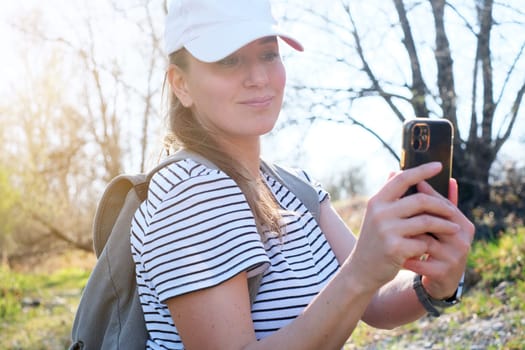 Happy woman traveler with backpack taking selfie during trekking trip in forest