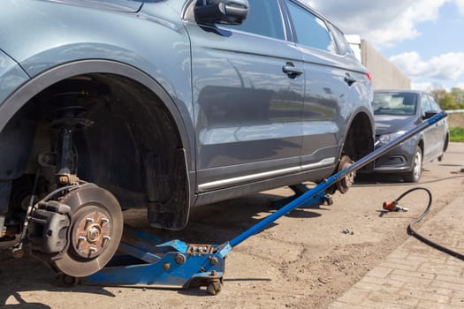 Two cars on tire mounting with removed wheel on pneumatic jack, seasonal tire change, car service concept.