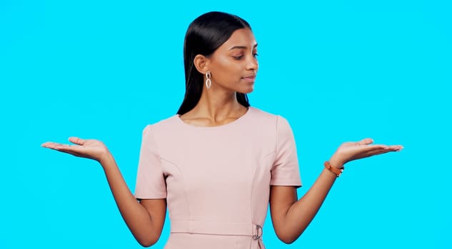 Choice, option or decision and a woman on a blue background in studio with a hand gesture. Portrait, balance and scale with an attractive young female weighing up the pros and cons of a variable