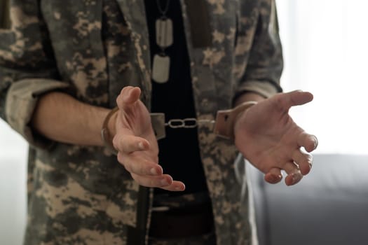 Handcuffed soldier in military army clothes. Close up of hands in handcuffs