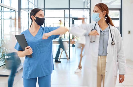 Covid healthcare doctor and nurse greeting with elbow in hospital clinic. Medical women or people with face mask and social distancing in corona virus pandemic for trust, motivation and innovation