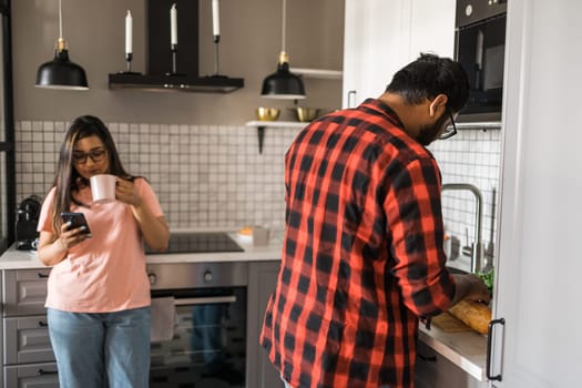 Millennial couple in quarrel and woman with smartphone ignoring each other having breakfast together at home, gadget overuse - communication problem family