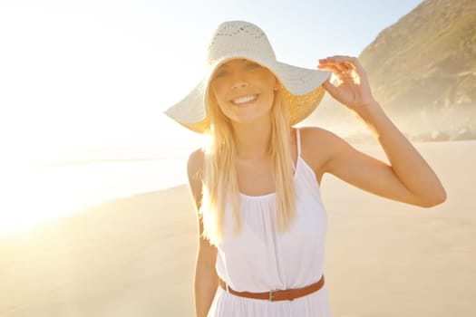 Feeling free in nature. Portrait of a gorgeous young woman wearing a white dress and sunhat on the beach.