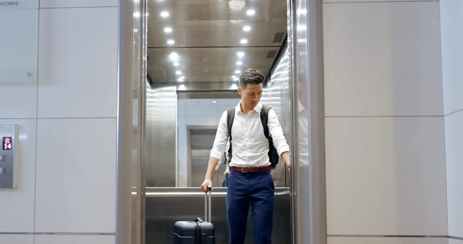 Elevator, travel and watch with a business asian man in an airport, checking the time of his flight for departure. Door, floor and late with a male employee holding suitcase luggage while traveling
