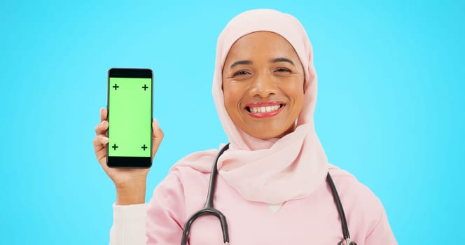 Green screen, phone and nurse isolated on blue background with medical mobile app, tracking marker and healthcare mockup. Happy islamic doctor or woman face with cellphone product placement in studio