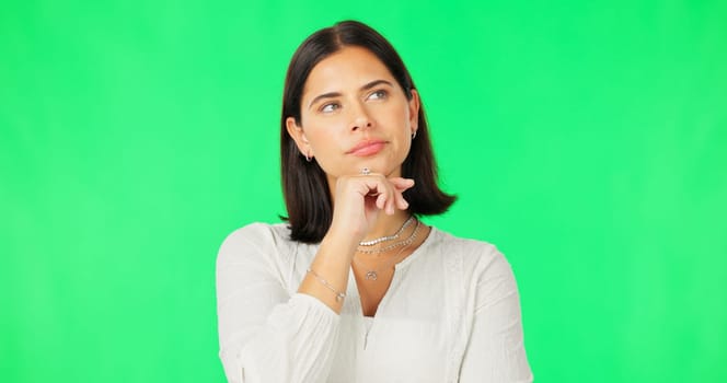 Face, idea and decision with a woman on a green screen background in studio to consider an option. Thinking, mind and contemplating with an attractive young female looking thoughtful on chromakey