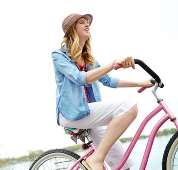 Exercise and fresh air. A young woman riding her bike next to a lake.