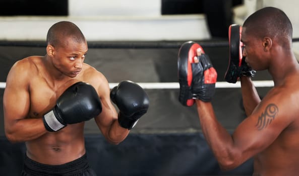 Lets take this to the next level. A focused young boxer sparring with his partner in protective gloves.