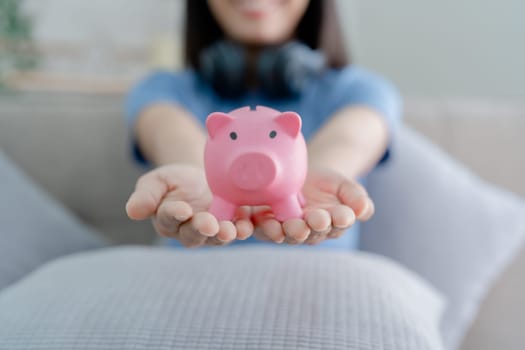 Asian young woman holding a piggy bank and coin, Savings concepts.