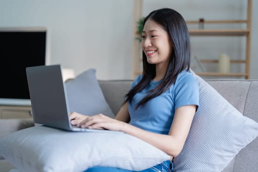 Asian Beautiful young woman relaxing on a couch at home with using computer laptop.
