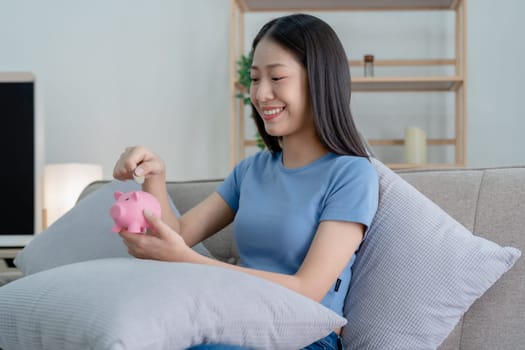 Asian young woman holding a piggy bank and coin, Savings concepts.