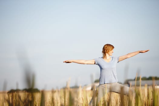 Staying strong, supple and flexible. an attractive woman doing yoga in a crop field.