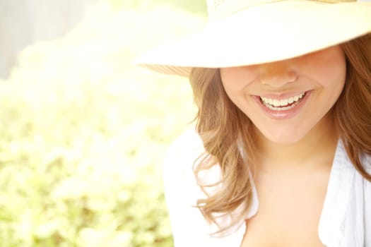 Gorgeous smile in the summer sun. A young teenager with a perfect smile standing in the summer sun covered by her sunhat.