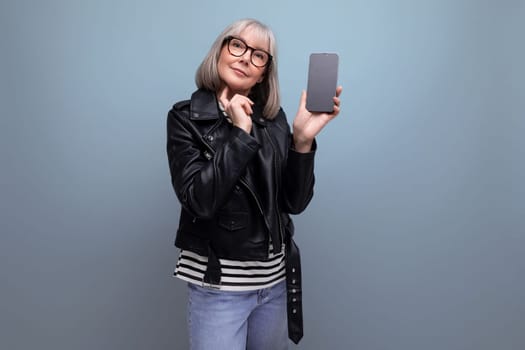 middle age business. 60s modern old lady with gray hair demonstrates a smartphone with a mockup on a bright background