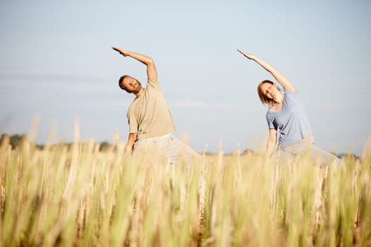 In perfect harmony. a mature couple enjoying a yoga workout in a crop field.