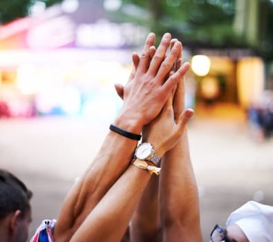 Cropped shot of a group of friends high-fiving at an outdoor festival.