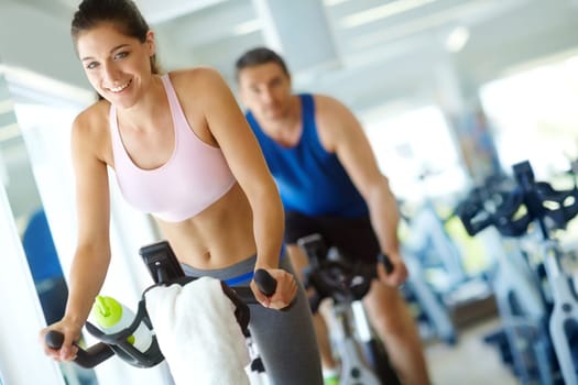 Spinning class gets my heart racing. A man and woman exercising in spinning class at the gym.