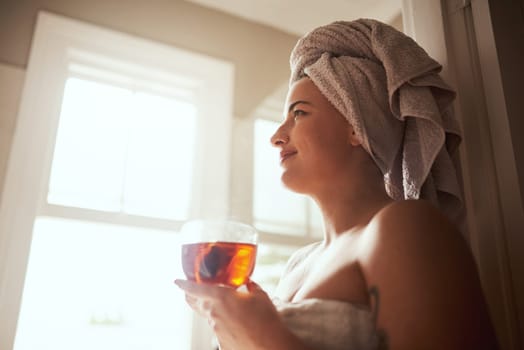 Tea makes every morning better. a young woman having tea while going through her morning beauty routine at home.