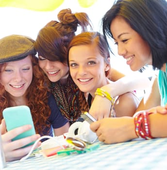 Teen technology. A group of adolescent girls laughing as they look at something on a smartphone screen.