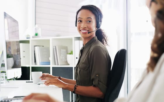 Creating happy clients one call at a time. a young woman using a computer and headset in a modern office.