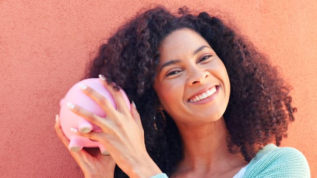 Piggy bank, cash and savings with a black woman listening to money in a pig outside on a pink wall background. Happy, smile and success with a young female confident with her finance and budget