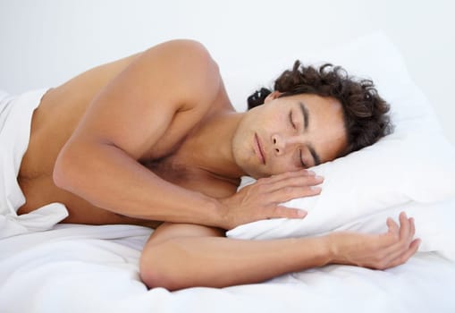 Rest, calm and man sleeping in bed on a weekend in the morning with a fluffy pillow at his house. Relax, peaceful and male person taking a nap and dreaming in the bedroom of his home or apartment.