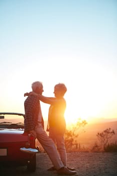 Making romance an important part of their lives. an affectionate senior couple enjoying the sunset during a roadtrip.