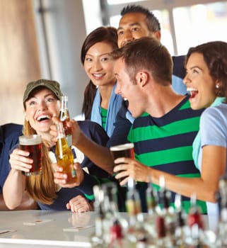 The cant get enough of sports and drinks. A group of excited friends cheering on their favourite team at the bar.