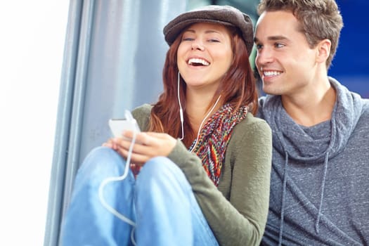 Relaxed and happy. a pretty girl listening to music on her phone while her boyfriend looks at her lovingly with copyspace.
