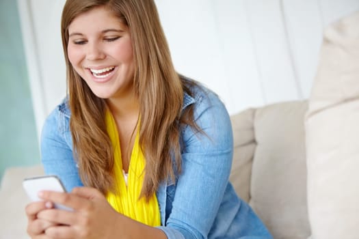 Hilarious. A pretty teenager reading a text message while relaxing on the couch - copyspace.