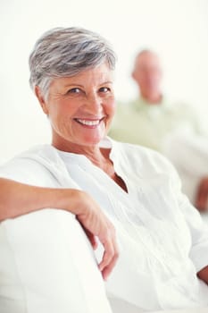 Relaxed mature woman smiling with man. Portrait of relaxed mature woman smiling with man in background.