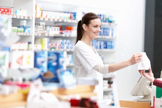 Pharmacist delivering the package to customer. Portrait of smiling female pharmacist delivering the package to the customer at store.